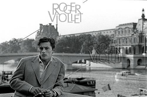 Roger-Viollet | 1643917 | Alain Delon (1935–2024), French actor, Quai Malaquais, Paris (6th arrondissement), circa 1958. Photograph by Philippe R. Doumic (1927–2013). | &copy; Philippe R. Doumic / Roger-Viollet