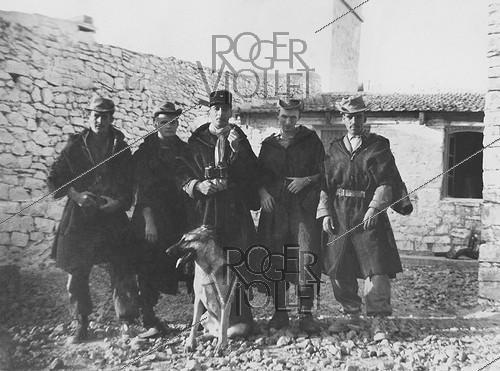 Roger-Viollet | 964098 | Algerian War of Independence. The French Army's fort in M'Zarouat, Mascara Area. The platoon included 48 harkis. The Sub-lieutenant Jean-Pierre Laffont, platoon commander, (in the middle) with his men and the fort's German shepherd. Algeria, Summer 1961. | &copy; Jean-Pierre Laffont / Roger-Viollet