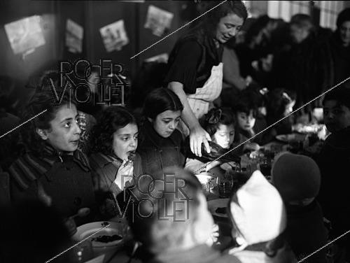 Roger-Viollet | 1421901 | Après-guerre 1939-1945. Distribution de goûters offerts par la Croix-Rouge américaine aux enfants du XVIIIème arrondissement. Paris, 22 février 1945. Fonds France Soir. Bibliothèque historique de la Ville de Paris. | &copy; Fonds France-Soir / BHVP / Roger-Viollet