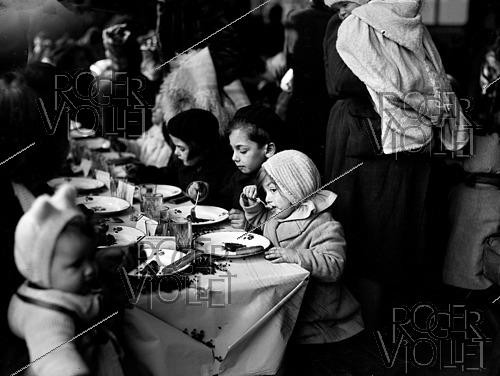 Roger-Viollet | 1421902 | Après-guerre 1939-1945. Distribution de goûters offerts par la Croix-Rouge américaine aux enfants du XVIIIème arrondissement. Paris, 22 février 1945. Fonds France Soir. Bibliothèque historique de la Ville de Paris. | &copy; Fonds France-Soir / BHVP / Roger-Viollet