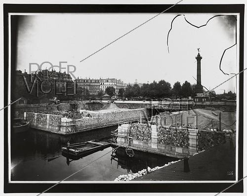 Roger-Viollet | 1055918 | Construction du chemin de fer métropolitain municipal de Paris : ligne 1, 3ème lot (156). Station de la Bastille. Vue prise de la rive gauche du canal Saint-Martin. Paris (XIème arr.), 2 juillet 1899. Photographie de Charles Maindron (1861-1940). Paris, bibliothèque de l'Hôtel de Ville. | &copy; Charles Maindron / BHdV / Roger-Viollet