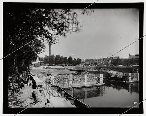 Roger-Viollet | 704893 | Construction du chemin de fer métropolitain municipal de Paris : ligne 1, 3ème lot (185). Station de la Bastille, vue prise de la rive droite du bassin de l'Arsenal. Paris (XIème arr.), 11 août 1899. Photographie de Charles Maindron (1861-1940). Paris, bibliothèque de l'Hôtel de Ville. | &copy; Charles Maindron / BHdV / Roger-Viollet