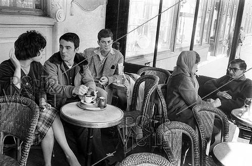Roger-Viollet | 959577 | French director Claude Chabrol and the actors of his first two movies at the café  Les Deux-Magot : Bernadette Lafont, Gérard Blain, Jean-Claude Brialy and Juliet Mayniel. Paris, April 1959. | &copy; Bernard Lipnitzki / Roger-Viollet