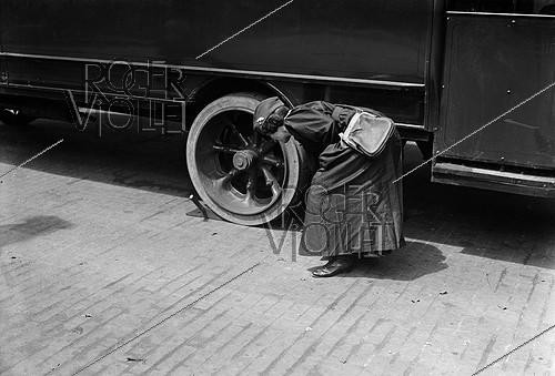 Roger-Viollet | 681974 | Guerre 1914-1918. Femme receveuse d'autobus vérifiant les roues de son véhicule. Paris. | &copy; Maurice-Louis Branger / Roger-Viollet