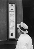 Roger-Viollet | 1061930 | Homme coiffé d'un canotier regardant un thermomètre indiquant 33°. | &copy; LAPI / Roger-Viollet