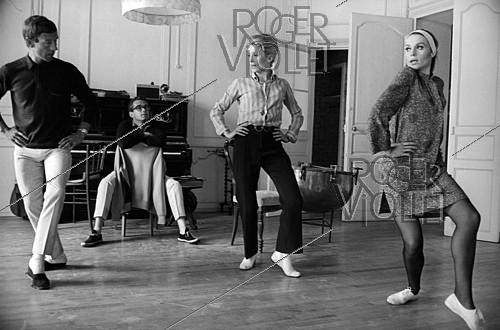 Roger-Viollet | 839551 | Michel Legrand (seated), Norman Maen, Catherine Deneuve and Françoise Dorléac during the shooting of  Les Demoiselles de Rochefort , film by Jacques Demy. France, 1966. Photograph by Georges Kelaïditès (1932-2015). | &copy; Georges Kelaïditès / Roger-Viollet