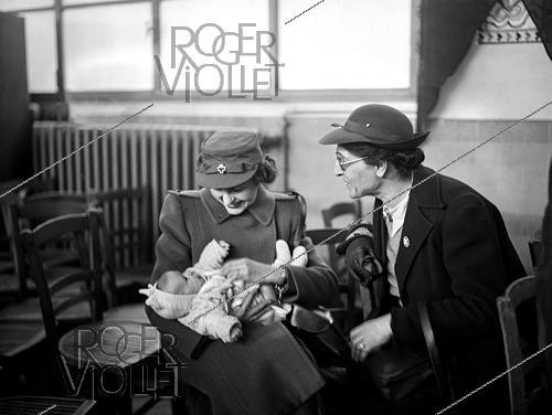 Roger-Viollet | 1421900 | Post WWII. Distribution of clothes offered by the American Red Cross to children from the XVIIIth arrondissement. Paris, on February 22, 1945. Photograph from the collections of the French newspaper  France-Soir . Bibliothèque historique de la Ville de Paris. | &copy; Fonds France-Soir / BHVP / Roger-Viollet